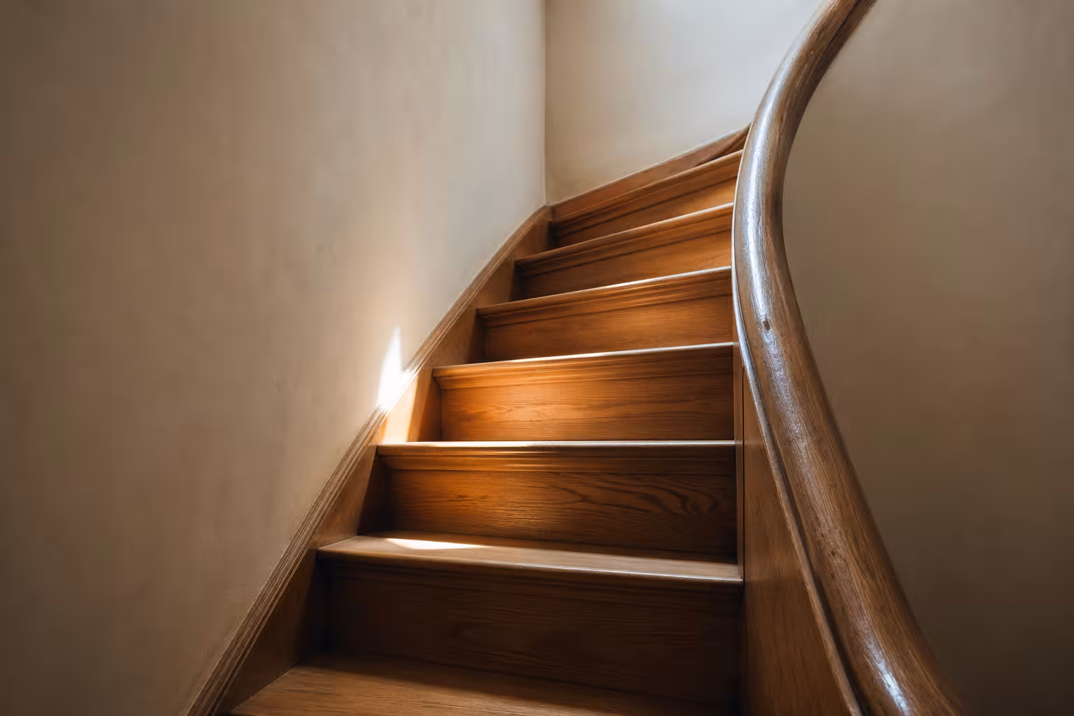 Escalier en bois d’une maison européenne ancienne, lumière naturelle descendante.